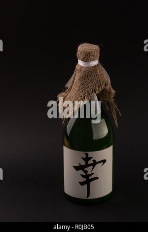 Die traditionellen Japanischen Reis alkoholische Getränk. Glasflasche mit Hieroglyphen auf schwarzem Hintergrund Stockfoto