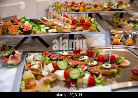 Catering Service am Tisch verschiedene Snacks auf einen Tisch am Bankett gesetzt. Der kalte Snacks, canape, Getränke, Nahaufnahme. Von der Seite. Bankett Tisch Stockfoto