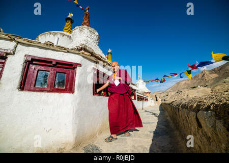 Ein Mönch, in roten Tüchern gekleidet, ist zu Fuß rund um lamayuru Gompa, die älteste und größte bestehende Kloster in Ladakh, Drehen Gebetsmühlen für relige Stockfoto