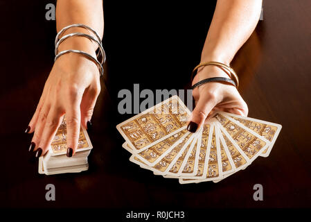 Wahrsagerin die Zukunft vorhersagen mit Tarot Karten halten Sie in Ihrer Hand aufgefächert, wie sie sich aus einer vollständigen Deck eine Nahaufnahme auf ihre Hände Stockfoto