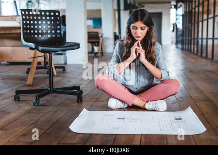 Konzentrierte junge geschäftsfrau, sitzen in Lotus Position und Arbeiten mit Papier im Büro Stockfoto