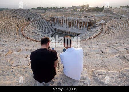 Zwei Männer mit ihren Smartphones auf die Ruinen des römischen Theaters in der antiken Stadt Hierapolis, Türkei Stockfoto