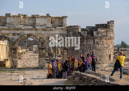 Muslimische Reisegruppe die Bilder vor der Ruine der Kriegslisten des Frontinus Tor in der antiken römischen Stadt Hierapolis, Türkei Stockfoto