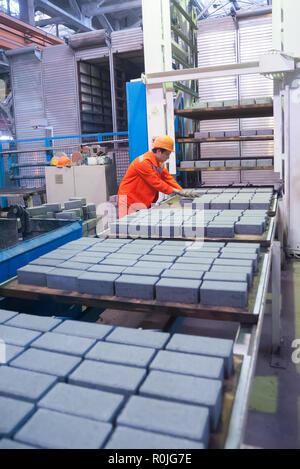 In Tjumen, Russland - 13. August 2013: Block machen Abteilung Bau Material factory ZHBI-5. Arbeiter an der Maschine auf Steinblöcke trocknen Stockfoto