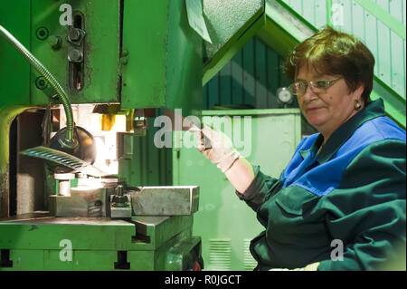 In Tjumen, Russland - 7. September 2010: JSC Tyumenskie Motorostroiteli. Anlage, bei der Herstellung und Reparatur von Flugzeugtriebwerken. Ältere Frau betreibt metalwor Stockfoto