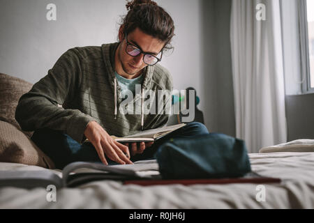 Student sitzt auf einem Bett und Studium mit Fokus und Konzentration. Junge Menschen die Vorbereitung auf die Prüfung, Bücher zu lesen. Stockfoto