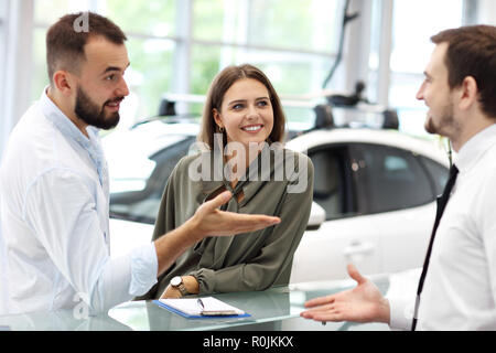 Selbstbewussten jungen Verkäufer erklärt Auto kennzeichnet den jungen attraktiven Besitzer Stockfoto