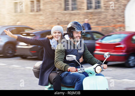 Schöne junge Paar Lächeln beim Reiten Roller in der Stadt im Herbst Stockfoto