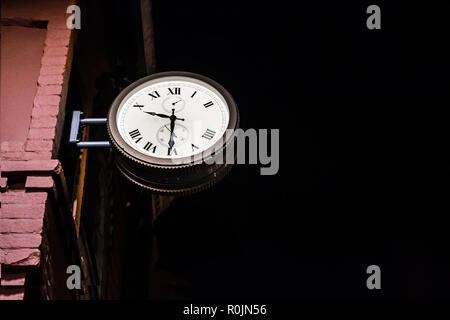 Straße Uhr auf eine Ziegelmauer Nacht angebracht. Stockfoto