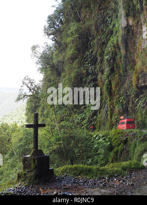 Rote Kleinbus und Kreuz auf Tod Road, die Welten die meisten gefährlichen Straße, auf dem Weg in die Yungas, La Paz, Bolivien, 14. November 2017 Stockfoto