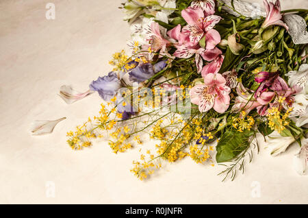 Blumenstrauß aus zarten, rosa Blüten von Alstroemeria mit lila Iris und gelbe Blumen der Hederich liegt schräg auf eine leichte Sperrholz Stockfoto