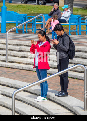 Asiatische Paar stehend auf Schritte mit Ihrer mobilen trephines am Coogee Beach Sydney NSW Australien. Stockfoto
