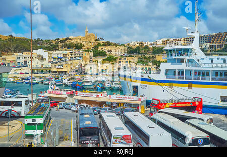 GHAJNSIELEM, MALTA - 15. JUNI 2018: Der Fährhafen der Insel Gozo ist ein lebhafter Ort mit vielen Touristenbusse, Reisebüros und Food Court für Arri Stockfoto