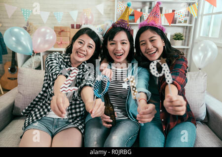 Attraktive Mädchen feiern Silvester Party. Junge Freunde, 2019 Anzahl in die Kamera lächelt fröhlich auf der Couch sitzen. Stockfoto