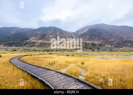 Holzsteg über den Mono Lake Tuffstein State Natural Reserve, der Sierra Berge und einem bewölkten Himmel im Hintergrund sichtbar; Kalifornien Stockfoto