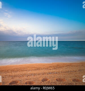 Spuren im Sand durch das blaue Meer Stockfoto