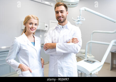 Junge männliche und weibliche Zahnärzte auf Kamera in der Zahnarztpraxis Stockfoto