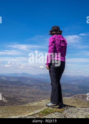 Eine reife Lady mit Blick auf die schottische Landschaft von einem Aussichtspunkt hoch auf den Hügeln bei einer Wanderung Stockfoto