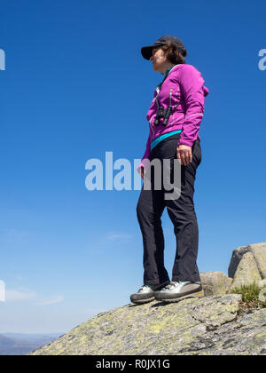 Eine reife Lady mit Blick auf die schottische Landschaft von einem Aussichtspunkt hoch auf den Hügeln bei einer Wanderung Stockfoto