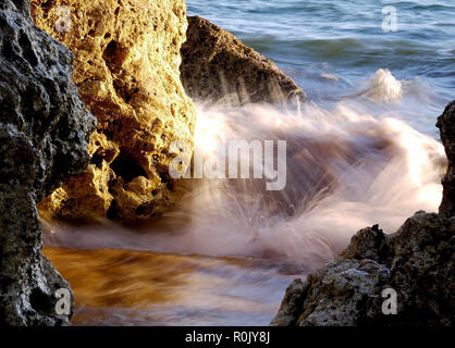 Wasser stürzt gegen Felsen am Strand in Portugal unter den Abend licht Stockfoto