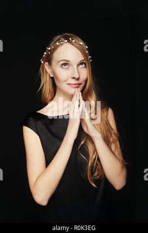 Lächelnd Preety Frau, die einen möchten die Hände zusammen, als ob sie beten auf schwarzem Hintergrund. Stockfoto