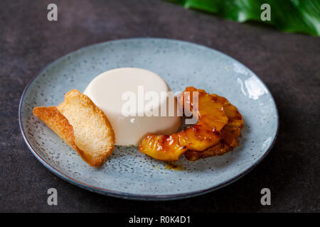 Panna cotta mit karamellisierter Ananas und Kokosnuss Keks Stockfoto