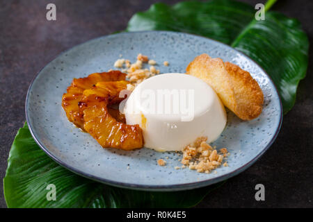 Panna cotta mit karamellisierter Ananas und Kokosnuss Keks Stockfoto