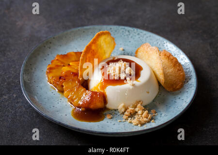 Panna cotta mit karamellisierter Ananas und Kokosnuss Keks Stockfoto