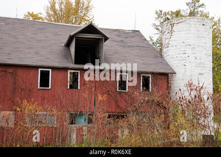 Verwitterte rot Verbot mit weißem Silo im Herbst Bäume abgebrochen Stockfoto