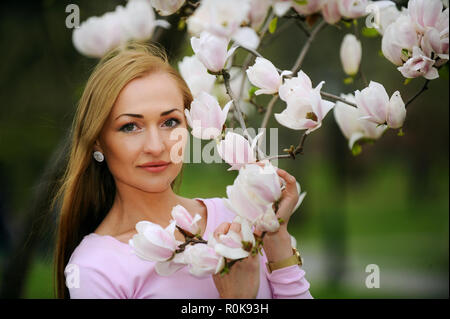 Schöne, Schöne und junge Frau an die Blüten der Bäume im Frühling. Stockfoto
