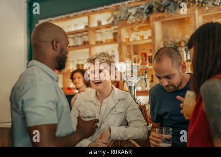 Gruppe von verschiedenen jungen Freunde lachen und reden über Cocktails, während gemeinsam in eine trendige Bar Stockfoto