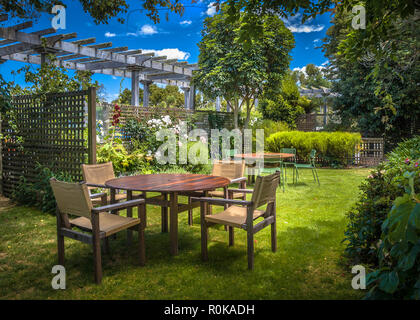 MARLBOROUGH, NEUSEELAND - 6. Dezember: Startseite Hinterhof mit Gartentisch im sonnigen einen üppigen Garten mit Schatten der Bäume im Sommer einstellen Stockfoto