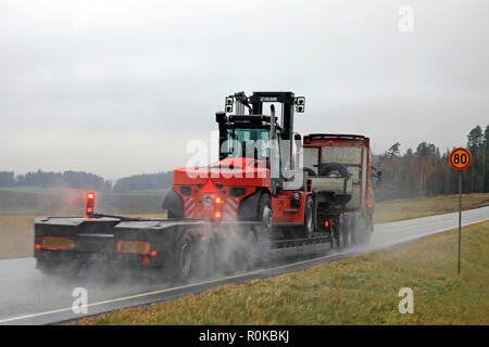 Salo, Finnland - 2 November, 2018: Scania Auflieger von Kosken Autokeskus schleppt große KALMAR Stapler auf nassen Autobahn an einem regnerischen Tag, Ansicht von hinten. Stockfoto