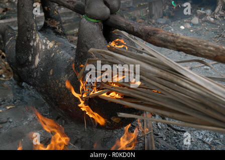 Mann, der versucht, ein Feuer zu beginnen Sie das Fell eines frisch geschlachteten Schwein, Honiara, Solomon Inseln zu brennen. Stockfoto