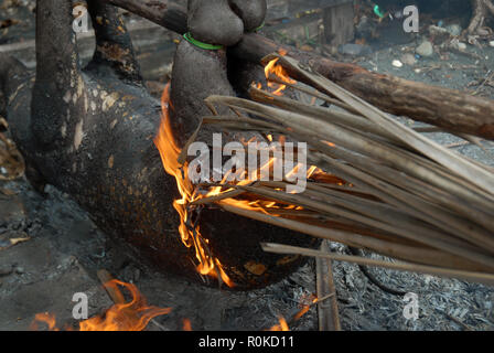 Mann, der versucht, ein Feuer zu beginnen Sie das Fell eines frisch geschlachteten Schwein, Honiara, Solomon Inseln zu brennen. Stockfoto