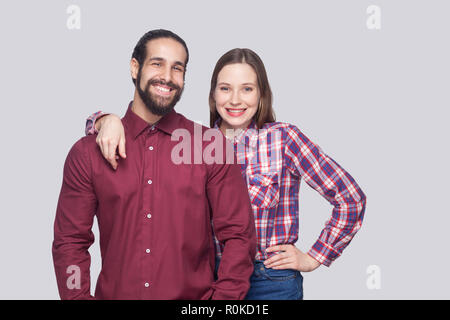 Portrait von glücklich, zufrieden, bärtigen Mann mit schwarzem Haar gesammelt und die Frau in der lässigen Stil stehen und an der Kamera mit toothy Lächeln. indoor s Stockfoto