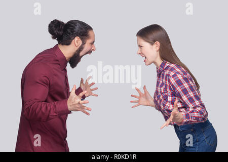 Profil Seitenansicht Portrait von Angry bärtiger Mann mit schwarzem Haar gesammelt und die Frau in der lässigen Stil stehen, suchen und Schreien an einander. ind Stockfoto