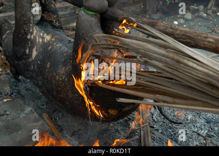 Mann, der versucht, ein Feuer zu beginnen Sie das Fell eines frisch geschlachteten Schwein, Honiara, Solomon Inseln zu brennen. Stockfoto