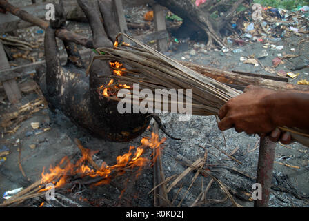 Mann, der versucht, ein Feuer zu beginnen Sie das Fell eines frisch geschlachteten Schwein, Honiara, Solomon Inseln zu brennen. Stockfoto