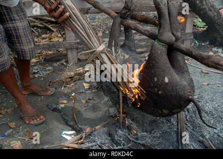 Mann, der versucht, ein Feuer zu beginnen Sie das Fell eines frisch geschlachteten Schwein, Honiara, Solomon Inseln zu brennen. Stockfoto