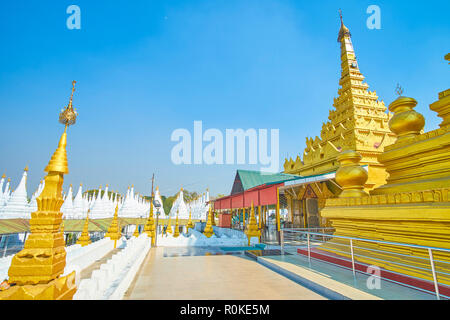 Der Innenhof der Kuthodaw Pagode Komplex mit hohen geschnitzten goldene Pagode mit Eingang zum Heiligtum, Mandalay, Myanmar Stockfoto