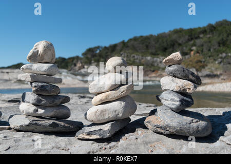 Ein Trio von der Felsen, oder Cairns, finden Sie ein empfindliches Gleichgewicht entlang der wunderschönen Küste von einer Quelle gespeiste Fluss in das Gebirge Central Texas. Stockfoto