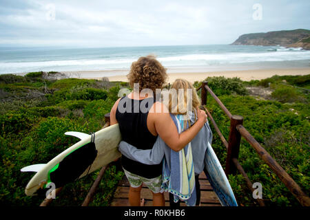 Surfer zu Fuß auf den Strand von einem Laufsteg Stockfoto