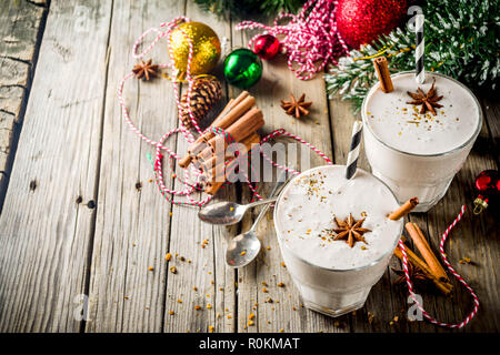 Weihnachten Süße kaltes Getränk, hausgemachter Eierlikör Milchshake in zwei Gläser mit Zimt und Anis, alte hölzerne Hintergrund mit Weihnachten Dekorationen Kopie Raum Stockfoto