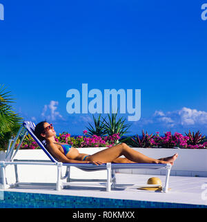 Junge Frau mit blauen Bikini Sonnenbaden auf Sonnenliegen am Pool, Guadeloupe, Französisch Westindien, Stockfoto