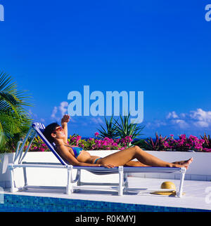 Junge Frau mit blauen Bikini Sonnenbaden auf Sonnenliegen am Pool, Guadeloupe, Französisch Westindien, Stockfoto