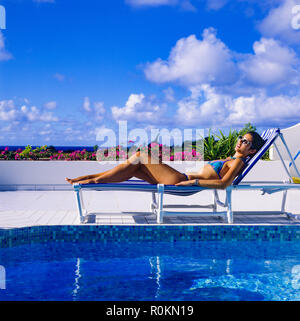Junge Frau mit blauen Bikini Sonnenbaden auf Sonnenliegen am Pool, Swimmingpool, Guadeloupe, Französisch Westindien, Stockfoto