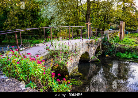 Eine kleine alte steinerne Brücke über den Fluss Coln, die Arlington Row von Bibury Dorf in Cotswold district, Gloucestershire, England führt, Großbritannien Stockfoto