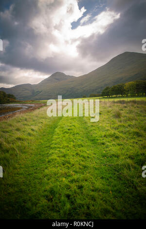 Ein Weg neben einem Loch in Richtung der Hügel in den Highlands von Schottland führt Stockfoto