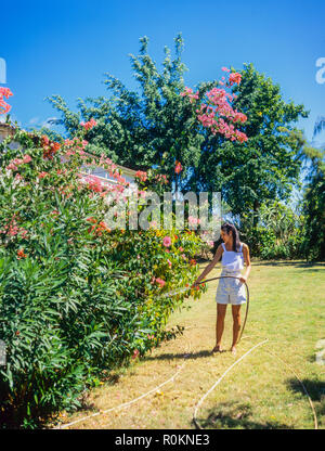 Junge Frau Bewässerung Blumen und Pflanzen, tropischen Garten, Guadeloupe, Französisch Westindien, Stockfoto